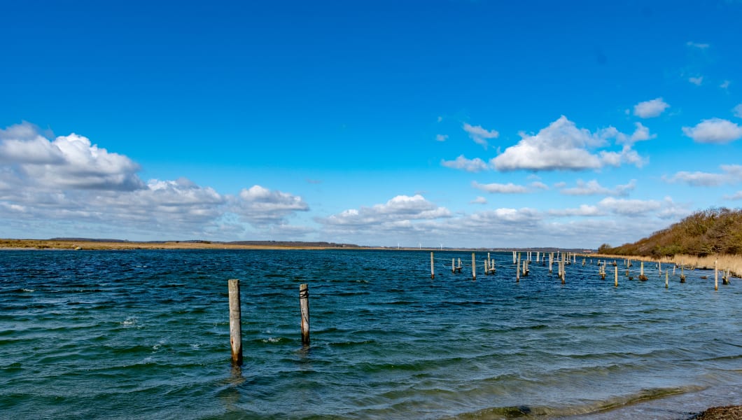 Beautiful Danish coastal landscape with wooden pier posts extending into serene blue waters